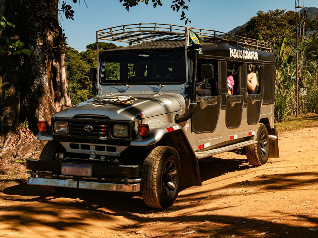Jeep 4x4 usado em passeio turístico por estrada de terra em Paraty, cercado por vegetação